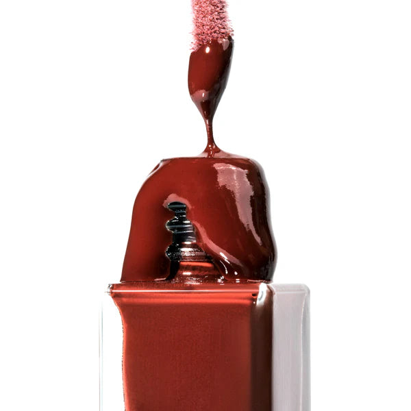 Close-up of Crunchi Hydrogloss Lip Oil oozing over the bottle rim with applicator visible, high-shine texture.