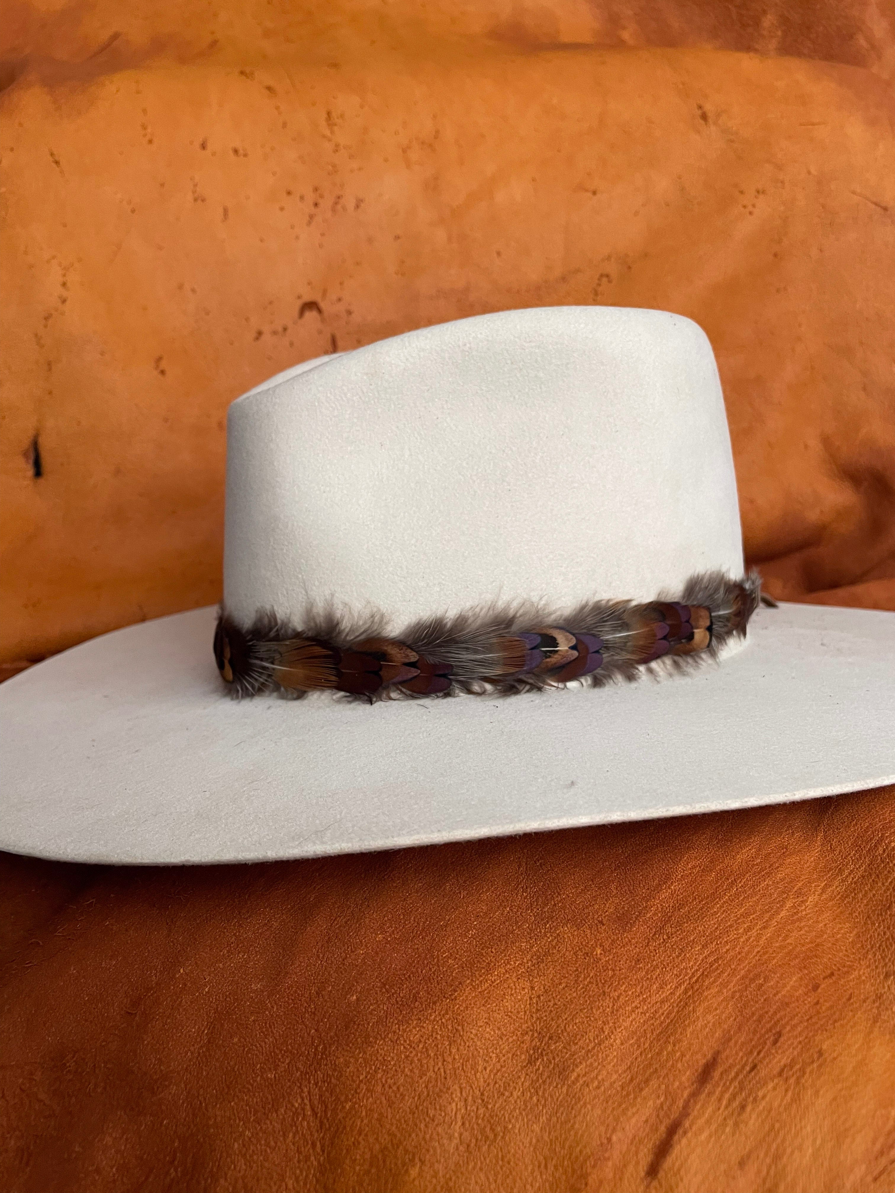 One-of-a-kind feather hatband with an amber sky color palette on an ivory felt hat. 