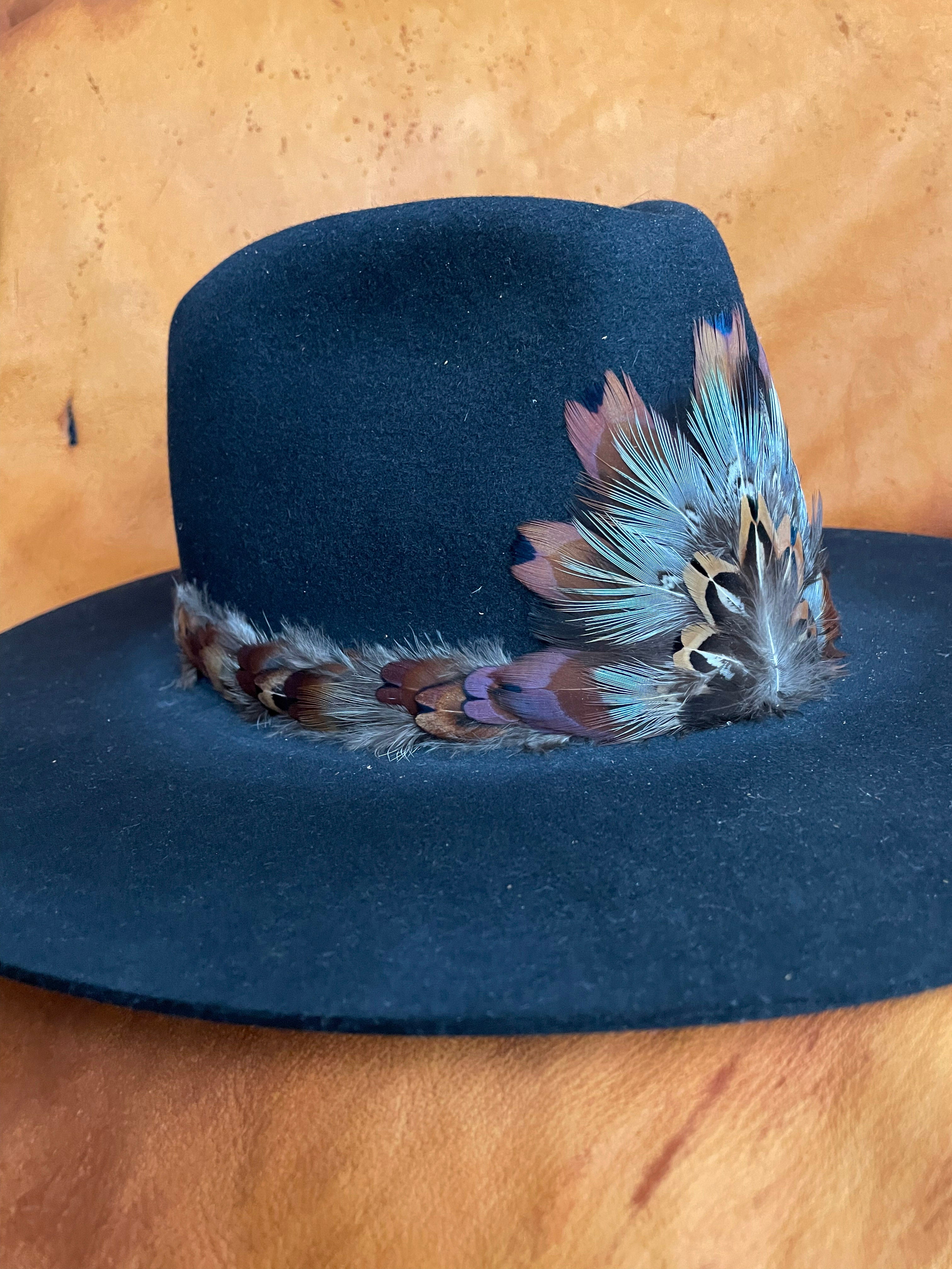 Feather medallion with contrasting warm and cool tones on a black felt hat. 
