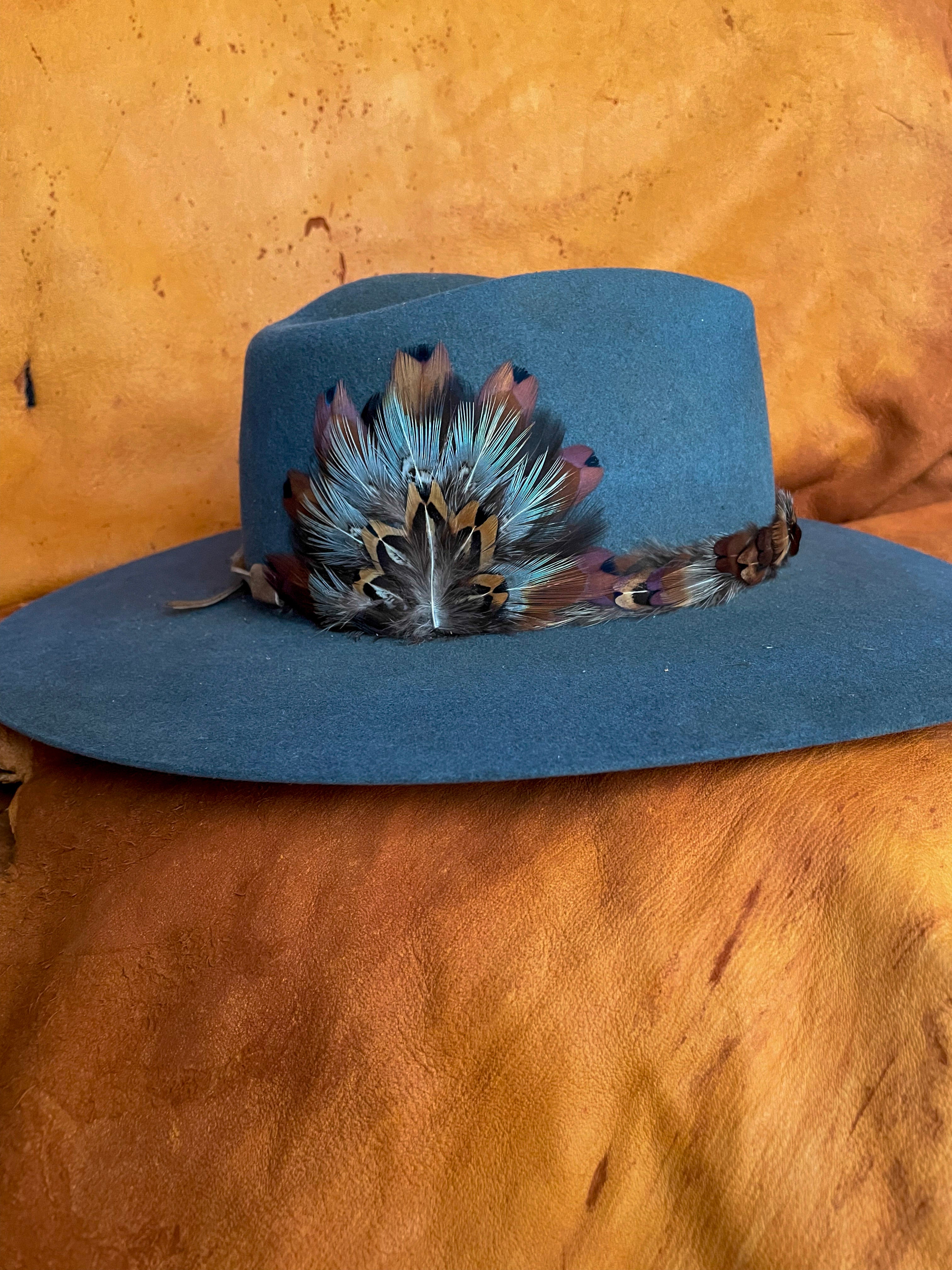 The side view of a steel blue felt hat with a one of a kind hatband and matching medallion. 