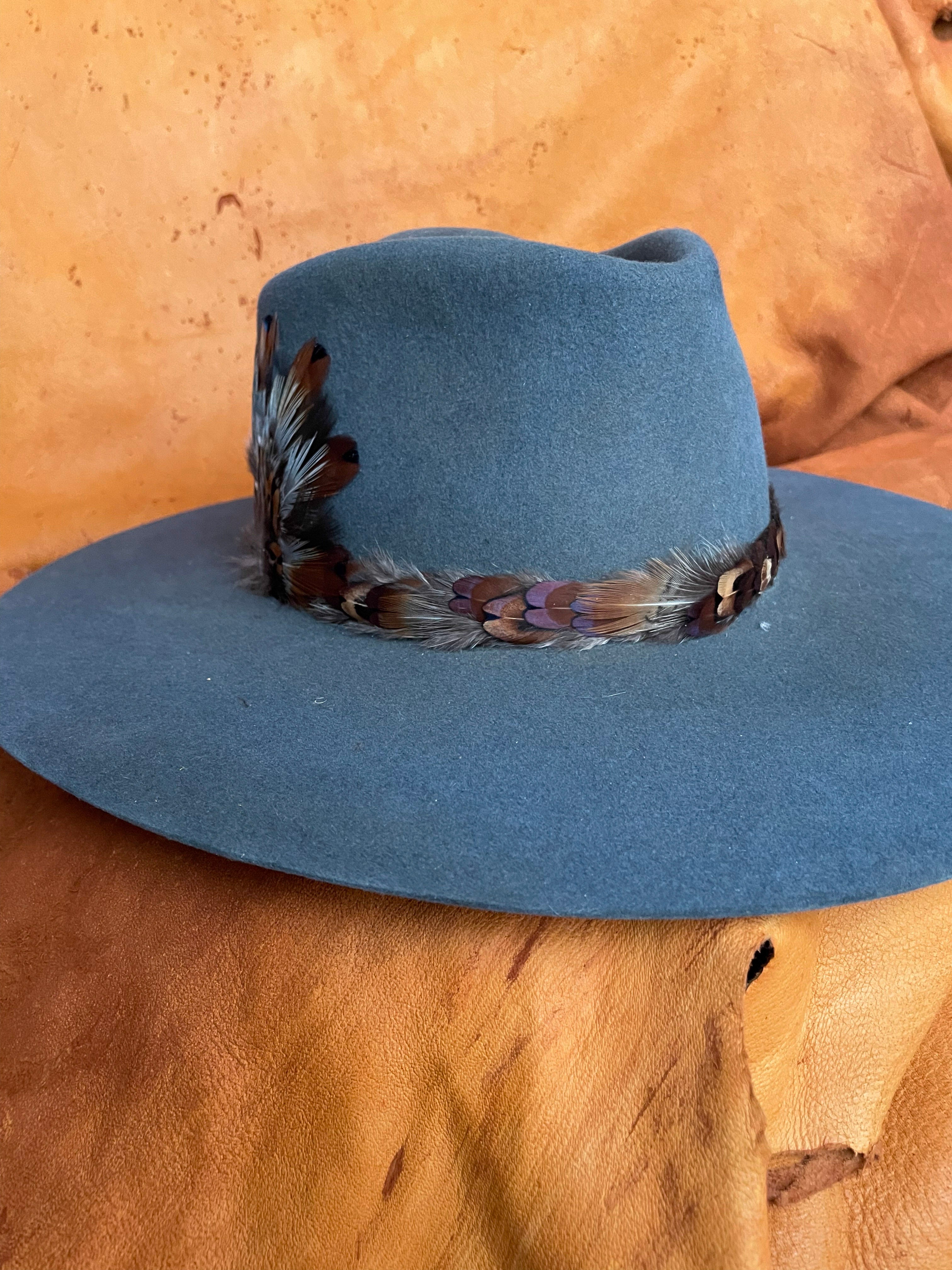 The front angle view of a steel blue felt hat with a one of a kind hatband and matching medallion. 
