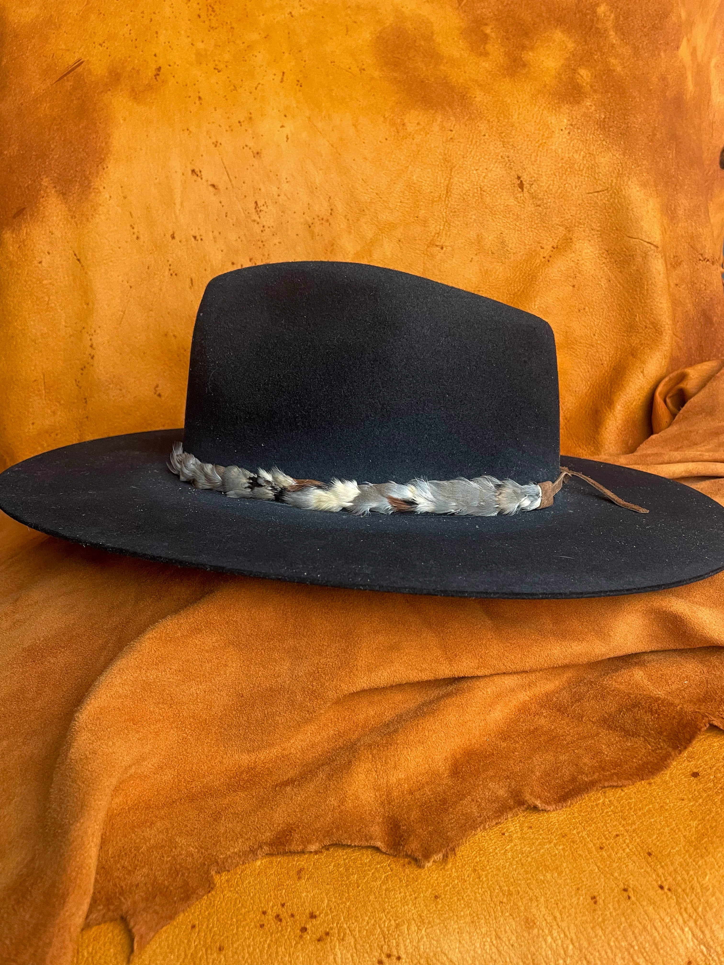 Handmade chukar feather hatband with blue, grey, and cream tones on a black felt hat. 