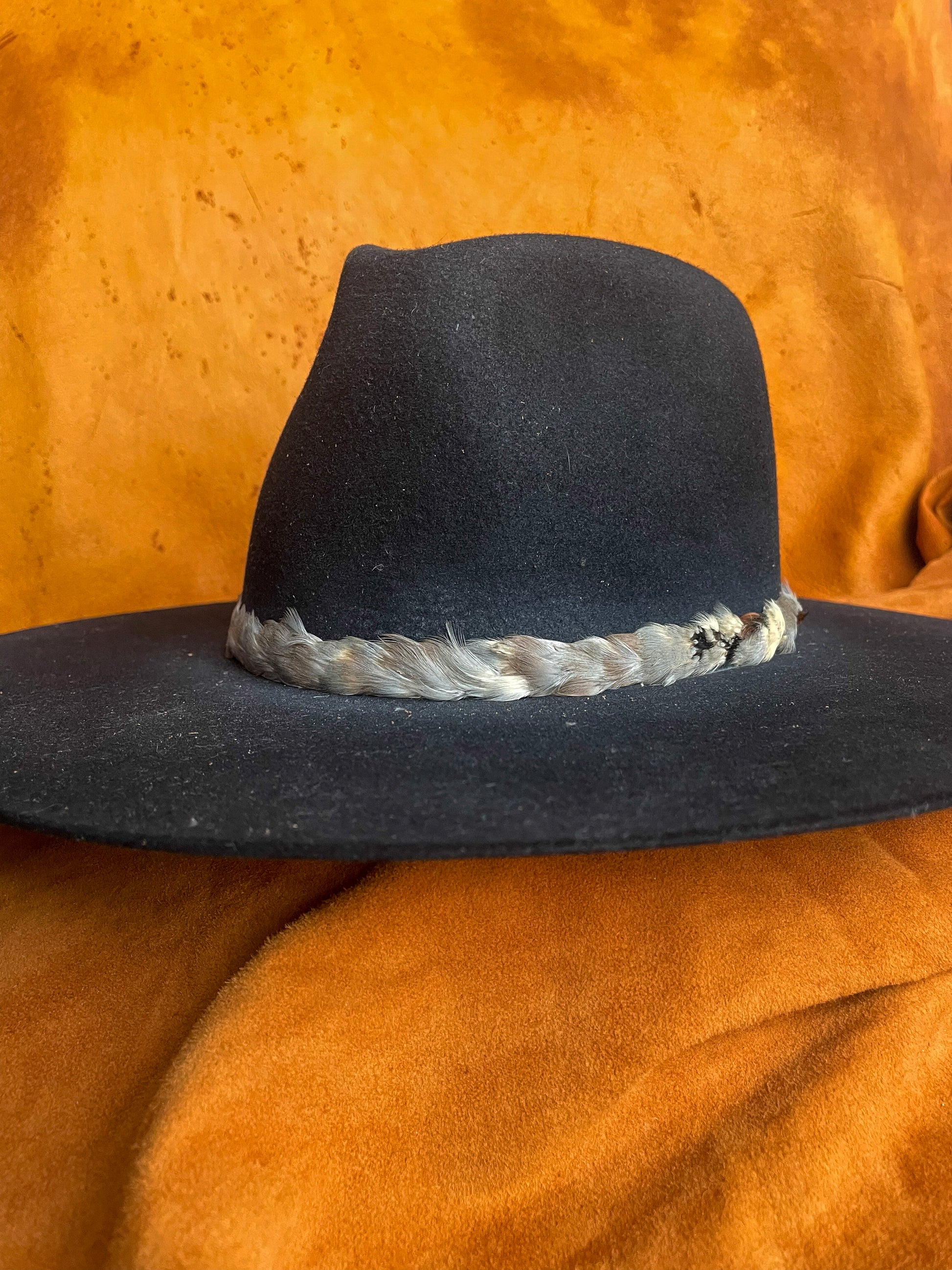 Natural feather band with understated color palette on a black felt hat. 