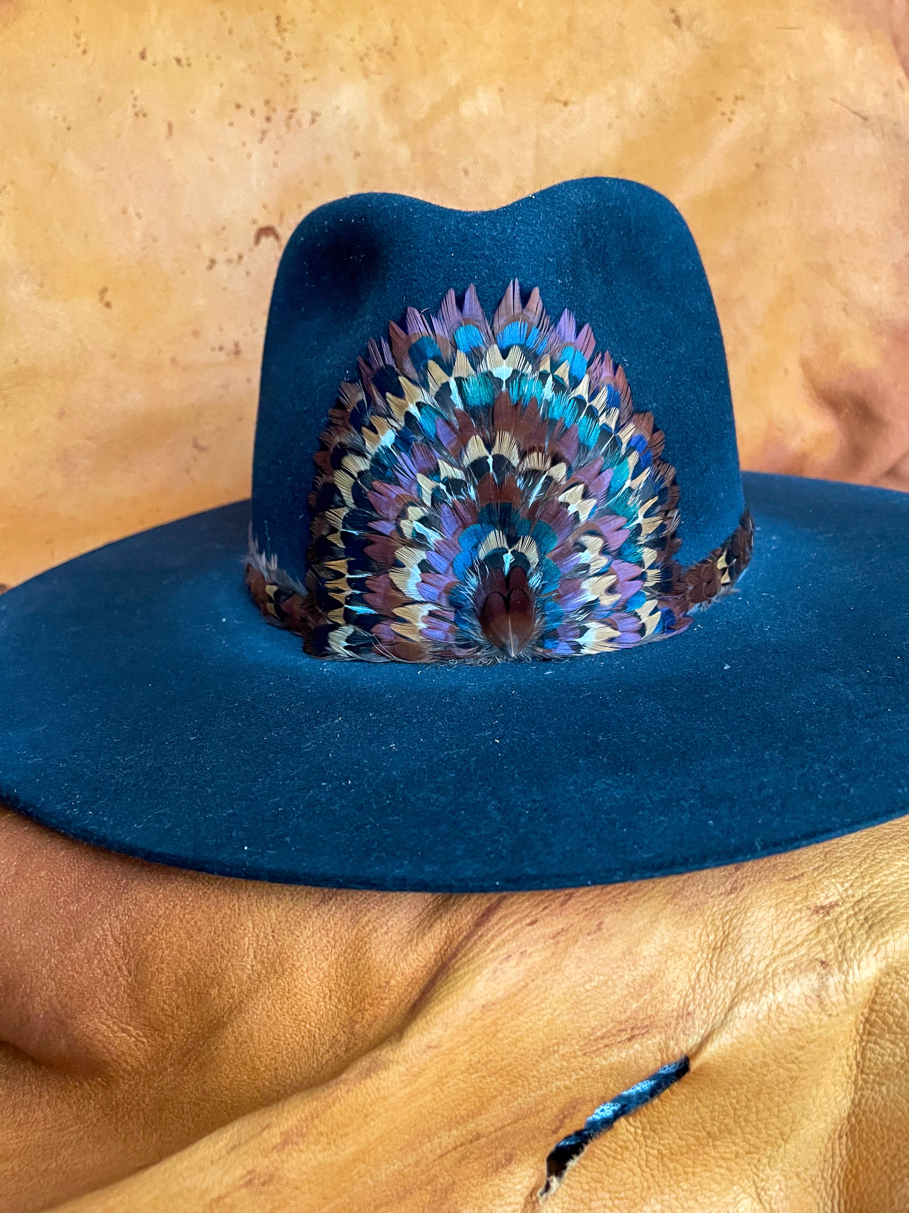 A front view of a one of a kind hatband and removable feather medallion on a black felt hat.