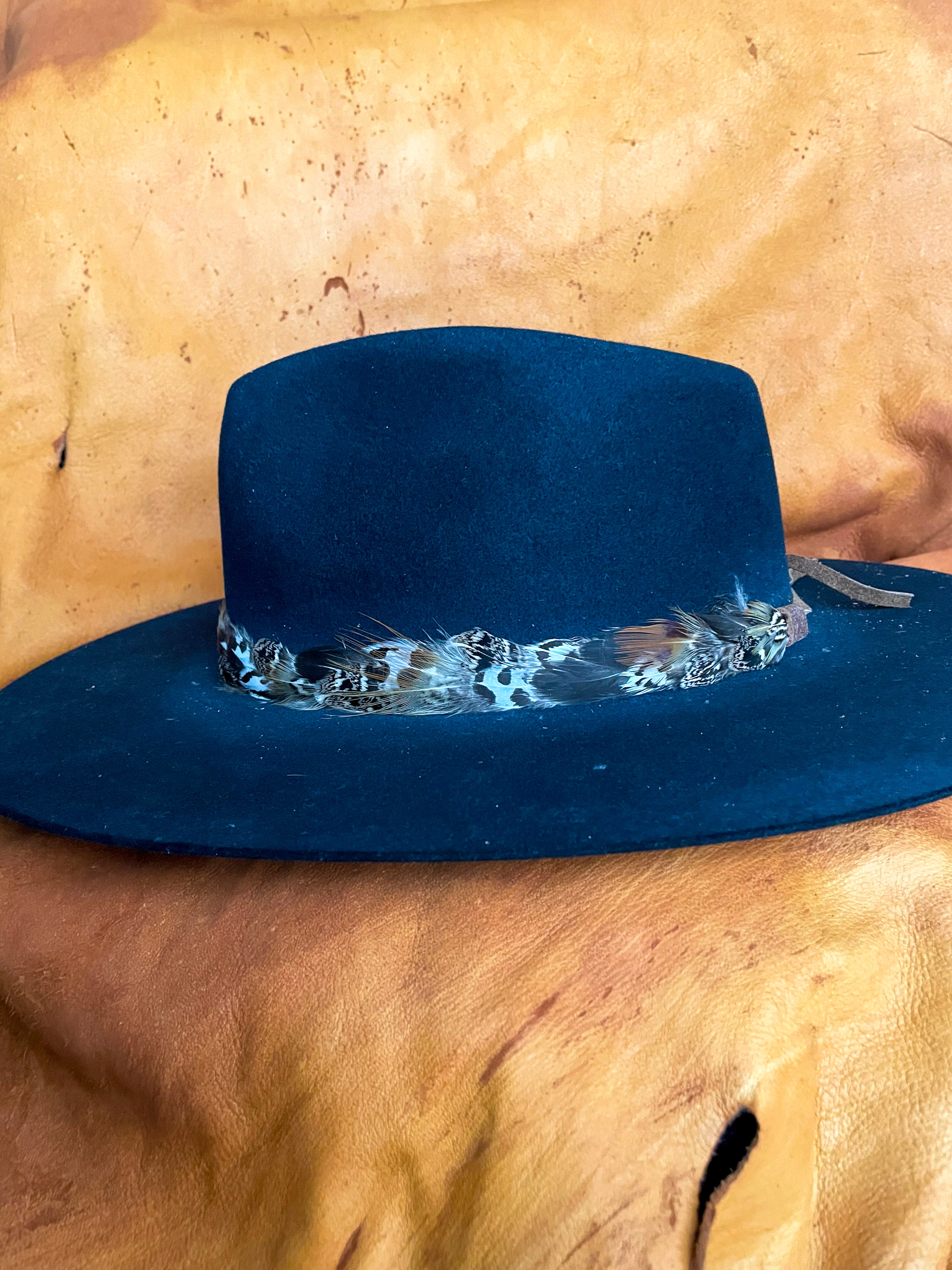 A sideview of a Sage Grouse and Pheasant feather hatband styled on a black felt hat.