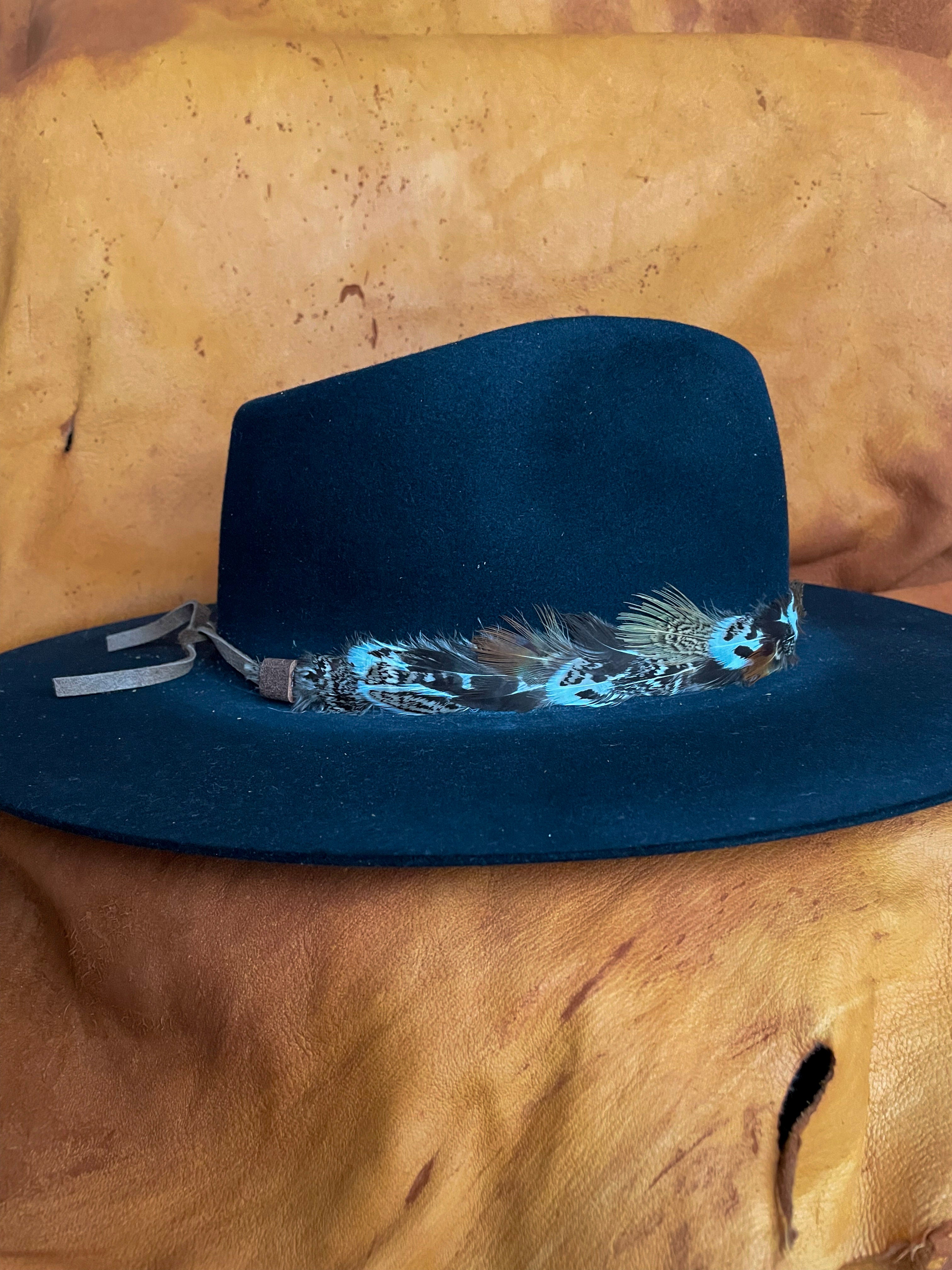 A sideview of a Sage Grouse and Pheasant feather hatband styled on a black felt hat with leather ties showing.