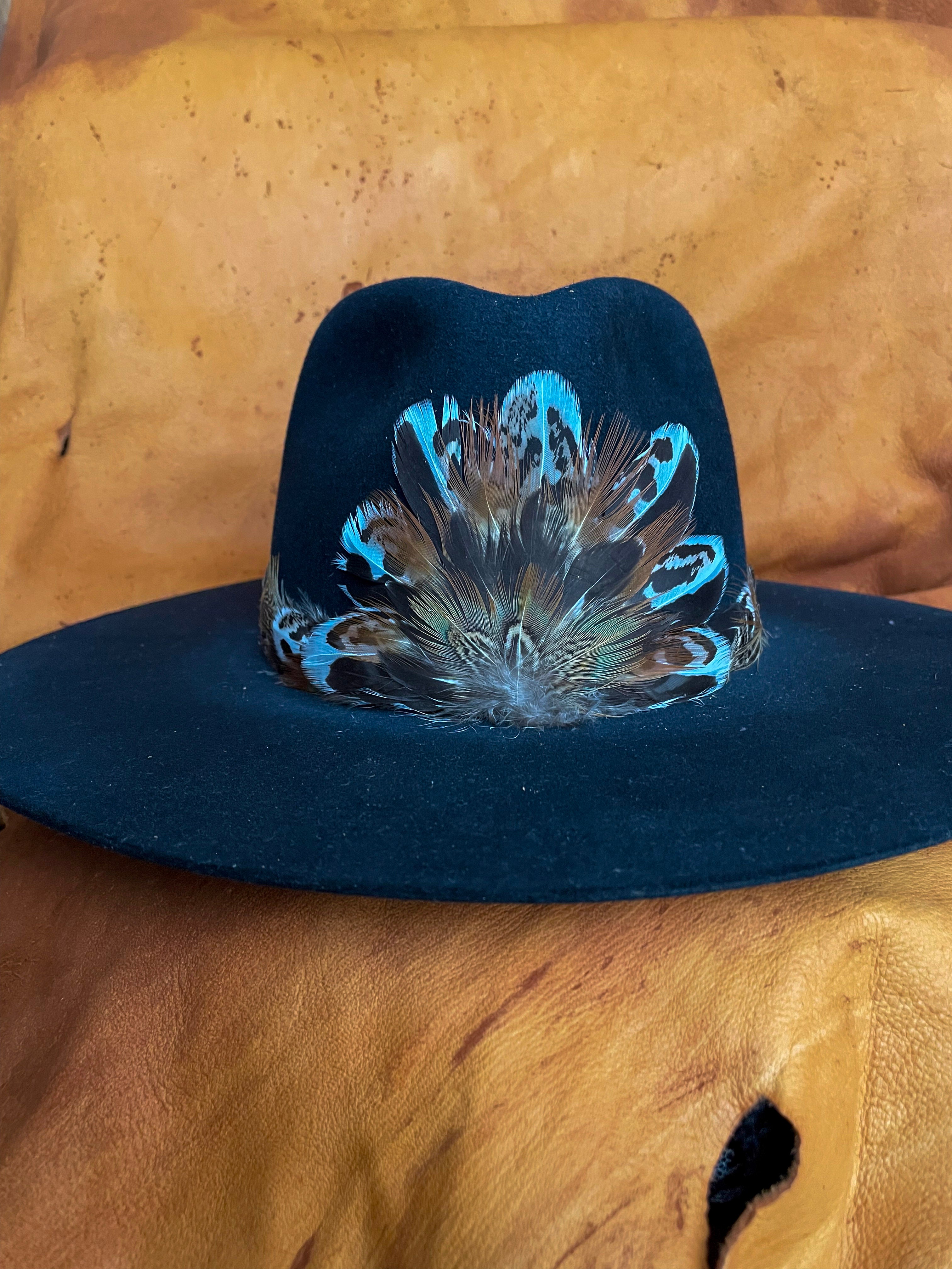 A Sage Grouse and Pheasant feather hatband and matching magnetic medallion styled on the front of a black felt hat.