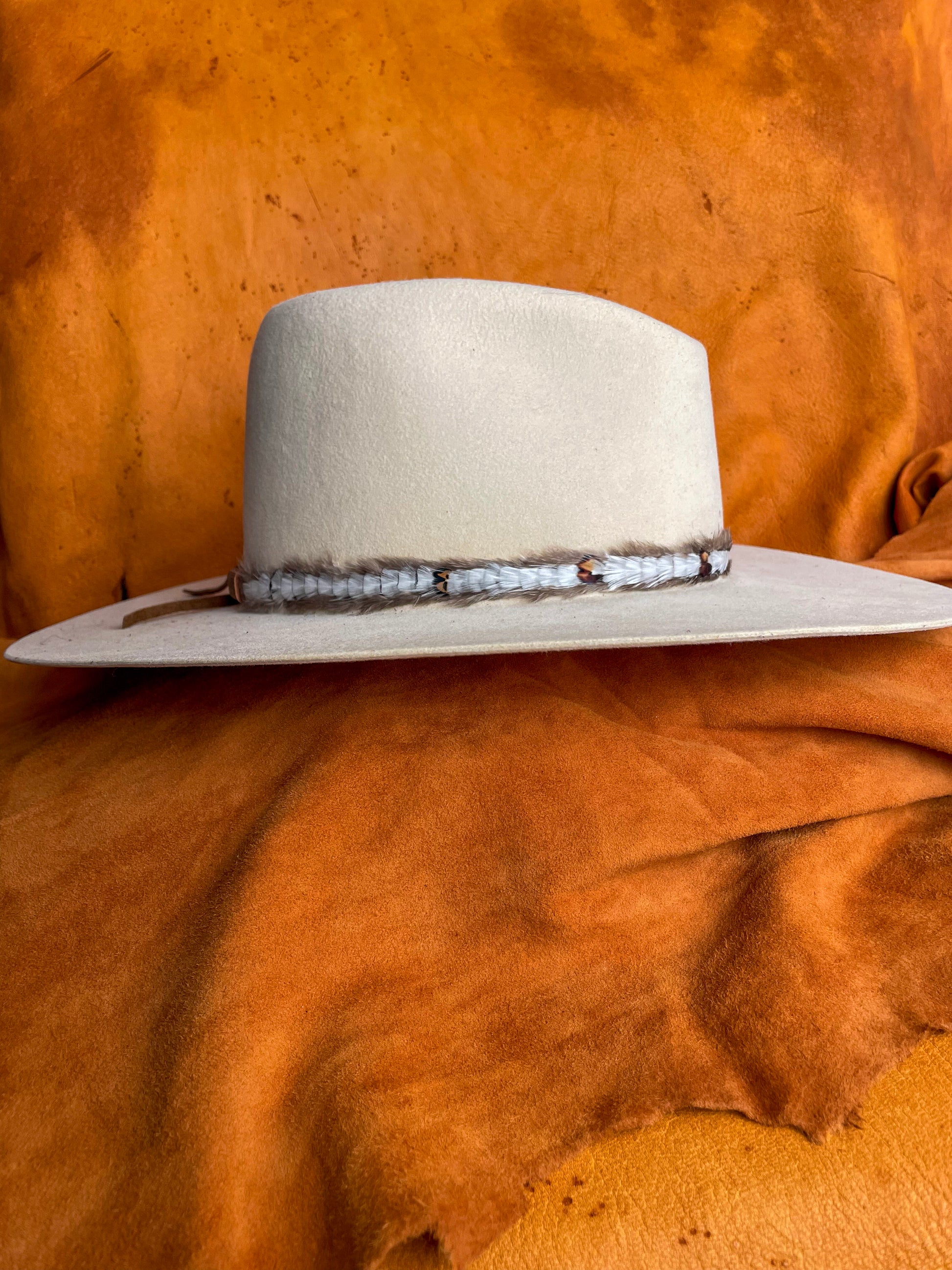 Side view of ivory feather band with natural variation on a creamy white hat.