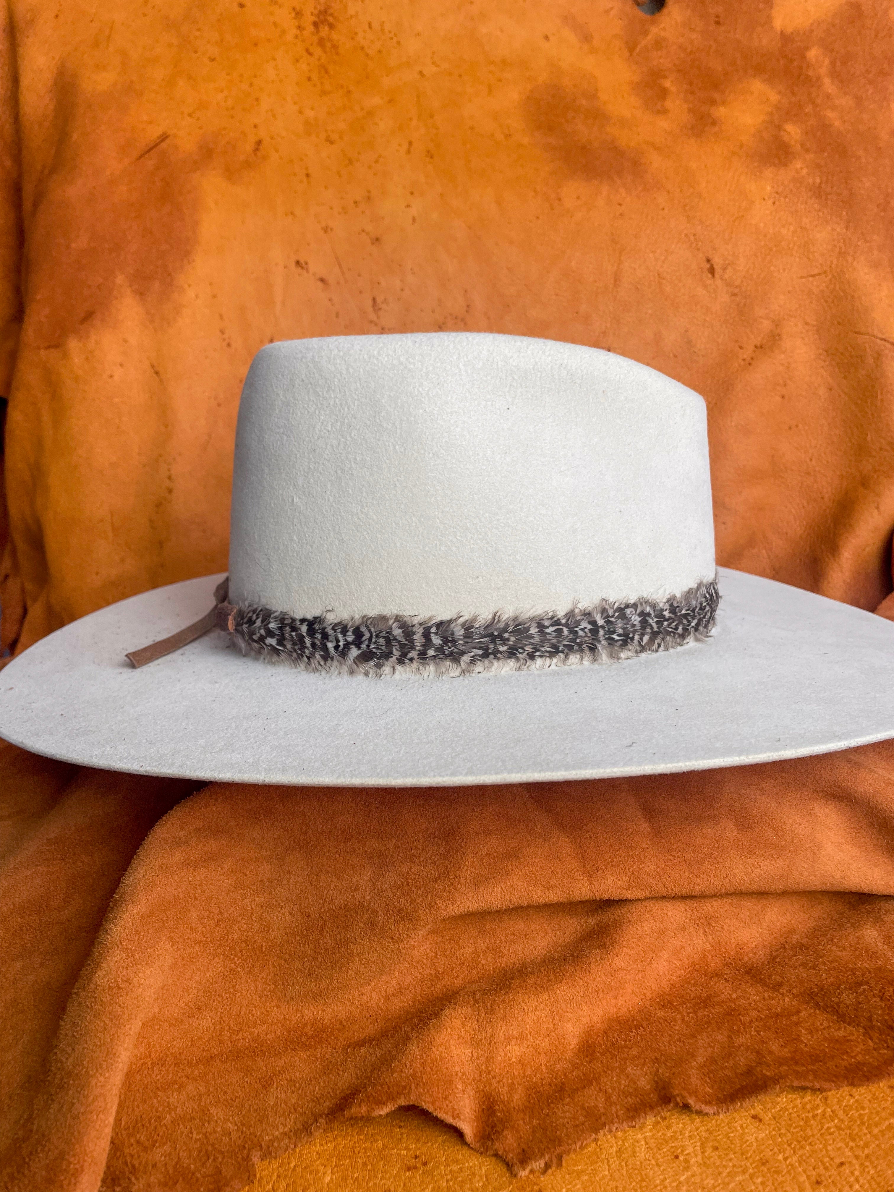 Feather band styled on cream felt hat with organic tones.