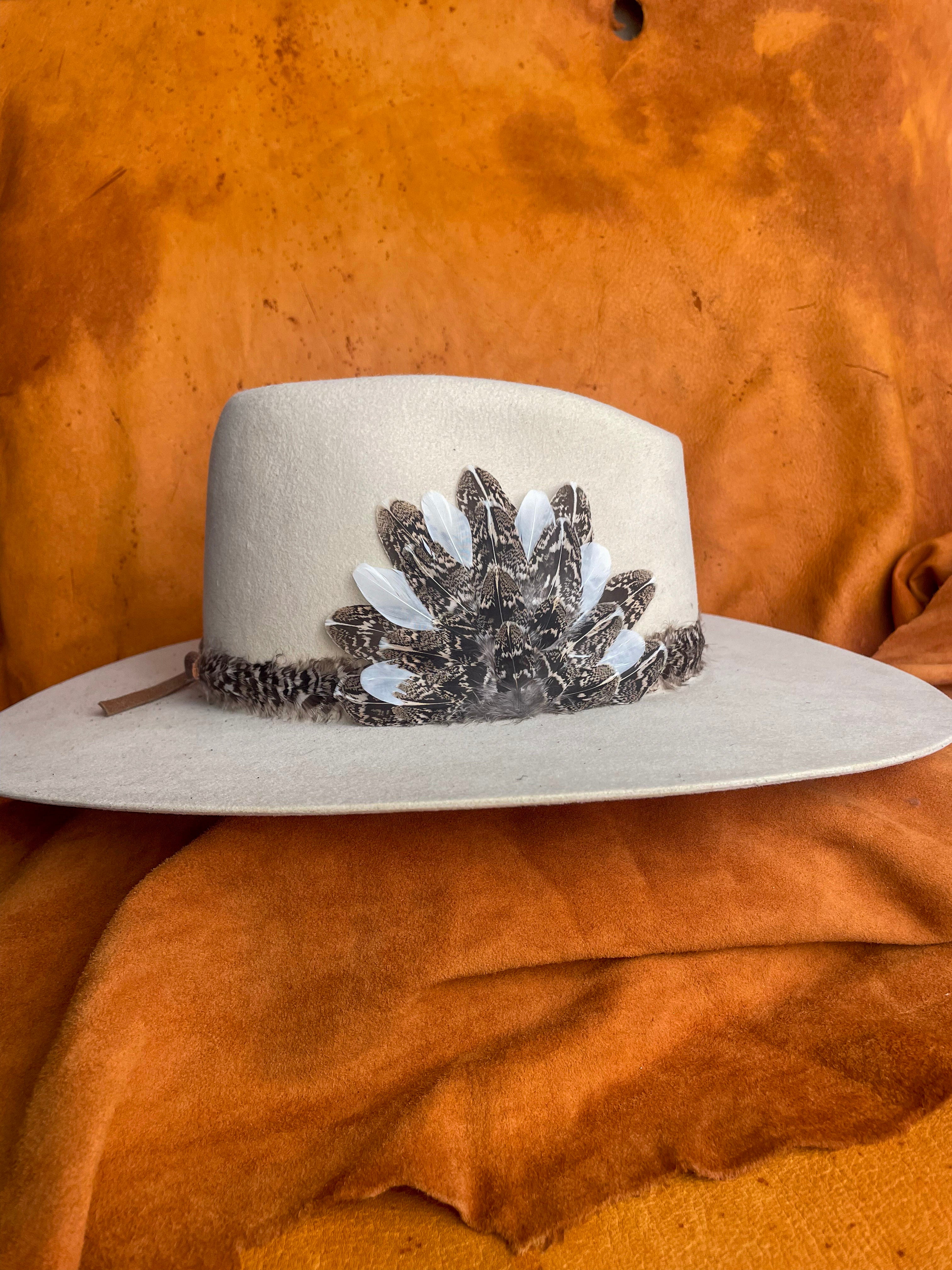 Feather band and magentic medallion styled on cream felt hat with organic tones.