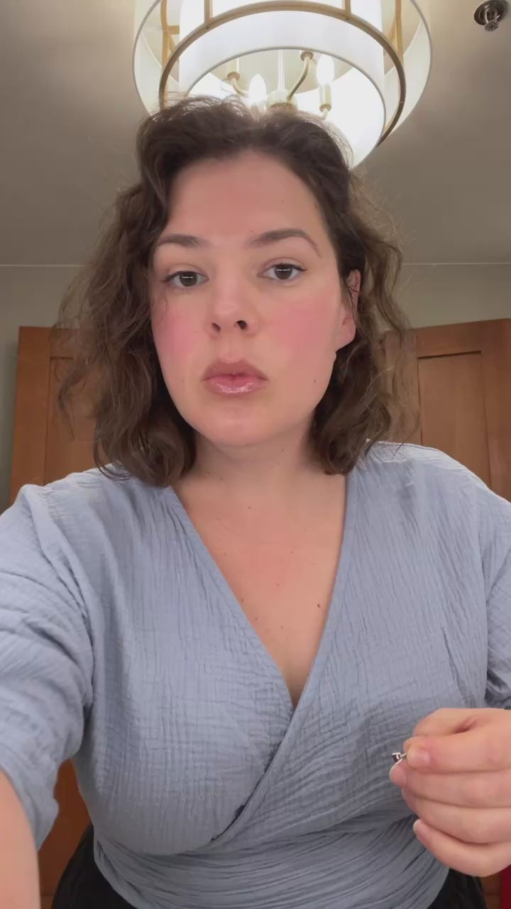 Short video of Olivia leaning toward the camera, putting on earrings, with text overlay: “Learn to Track Your Cycle & Feel in Sync” — inviting women into cycle awareness and confidence.