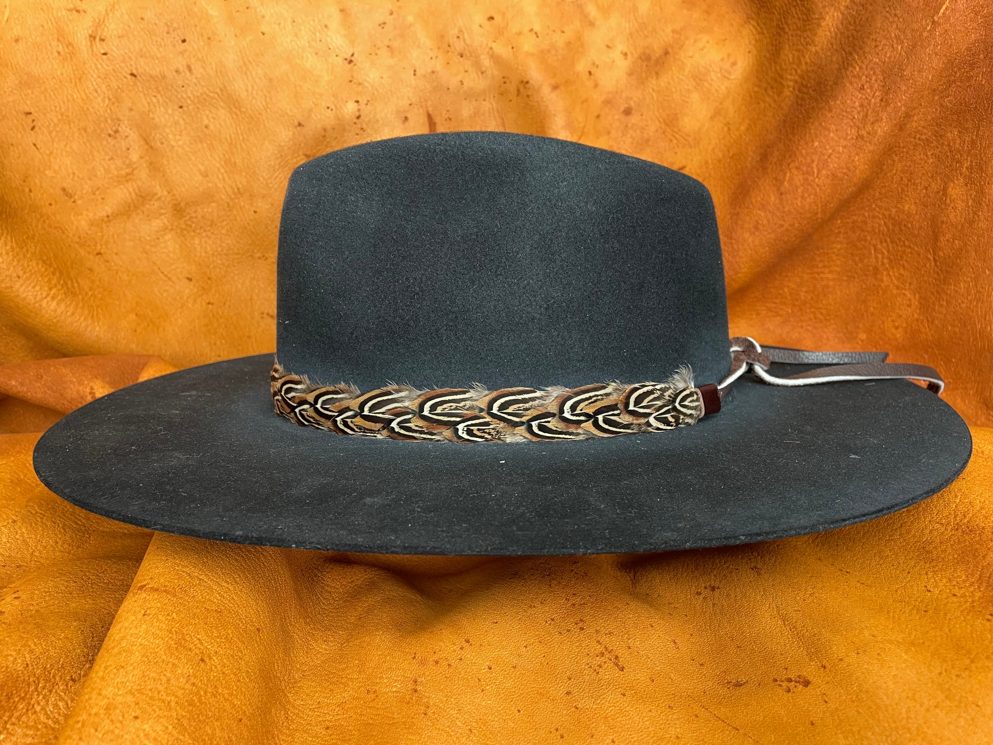 Golden/orange braided feather hatband on black hat, side angle
