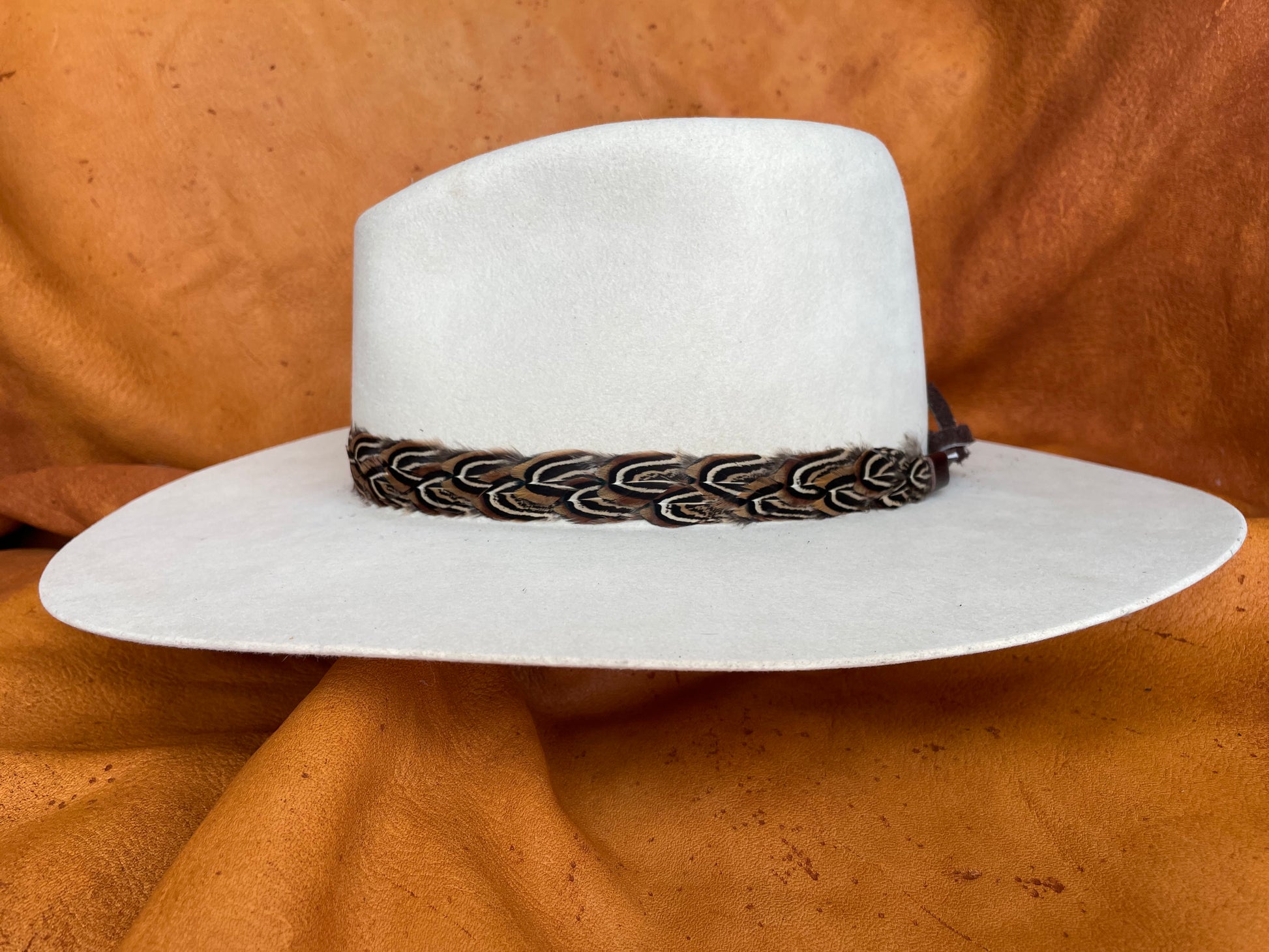 Rooster pheasant feather hatband with deerskin ties, side angle view