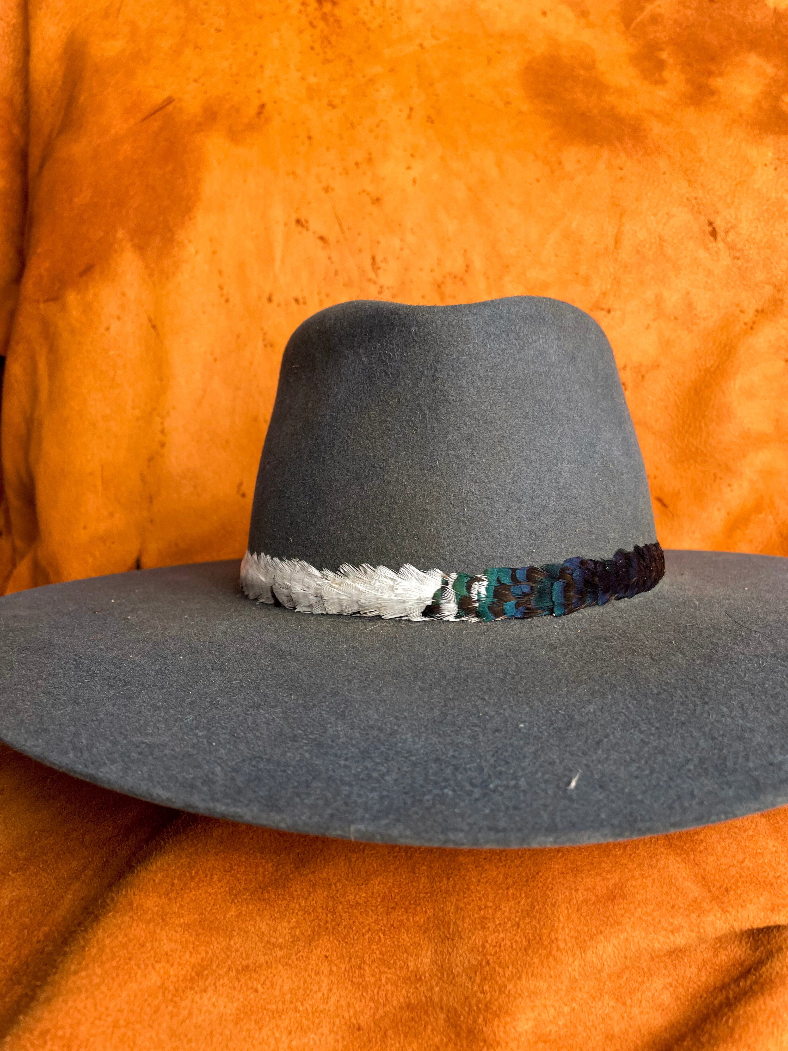Handmade feather hatband with green, white, and rust pheasant feathers on a steel blue hat. 