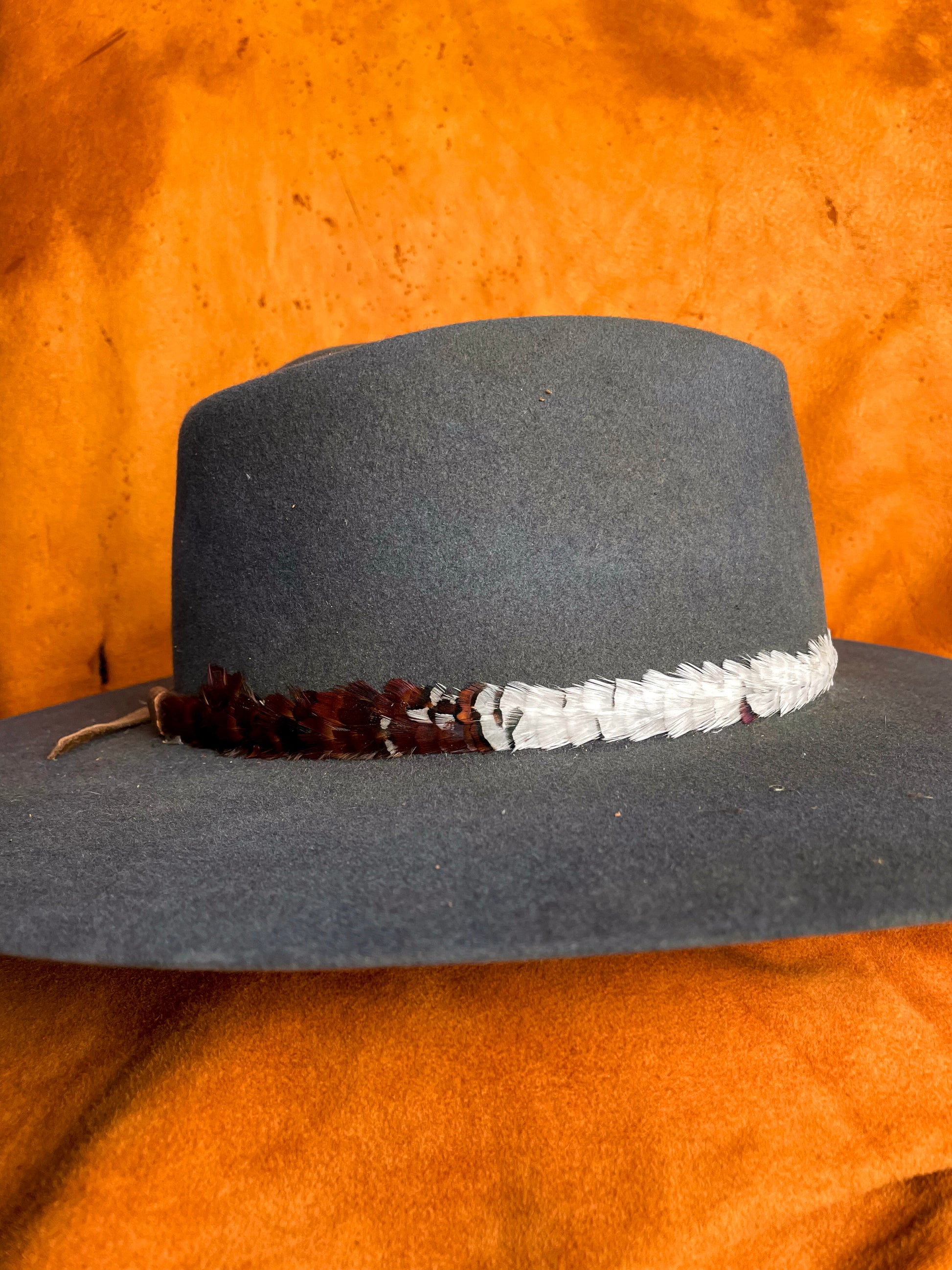 Side view of mixed feather tones in layered pattern on a steel blue hat. 