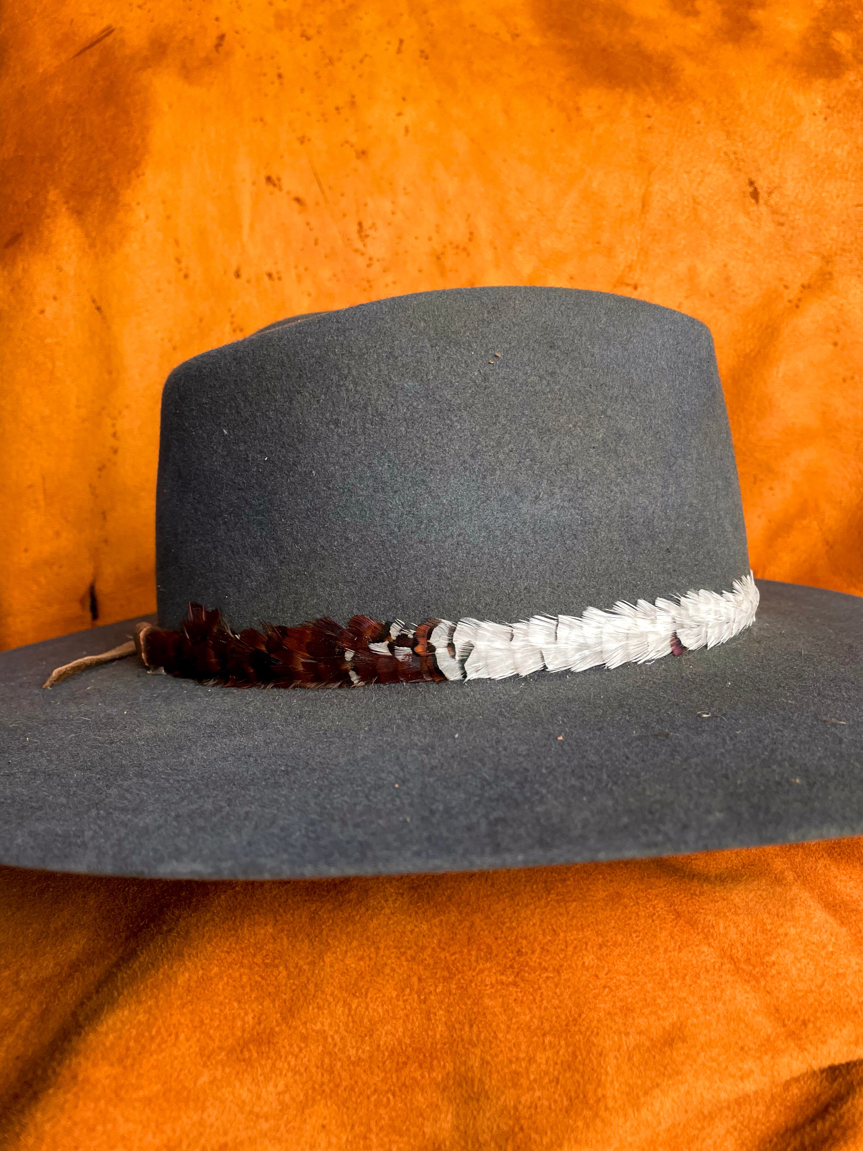 Side view of mixed feather tones in layered pattern on a steel blue hat. 