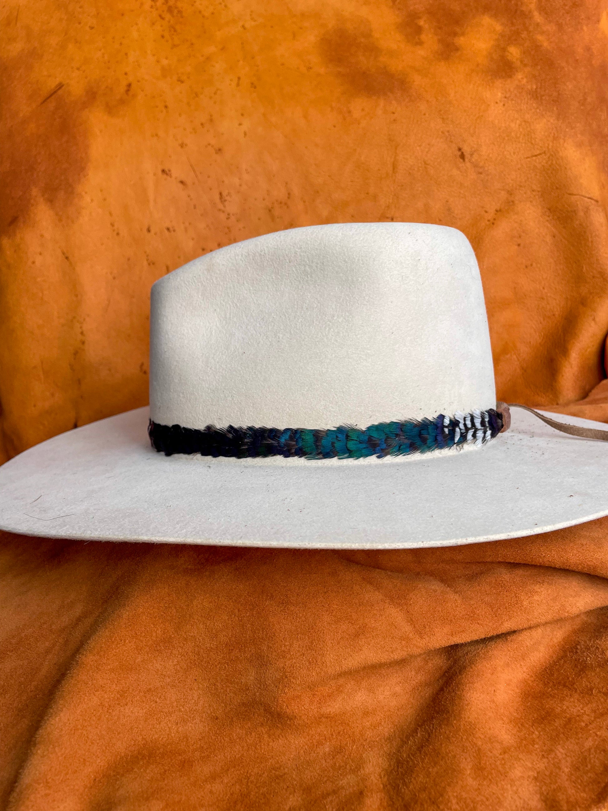 Color-block feather band, showcasing the emerald green block on a cream felt hat. 