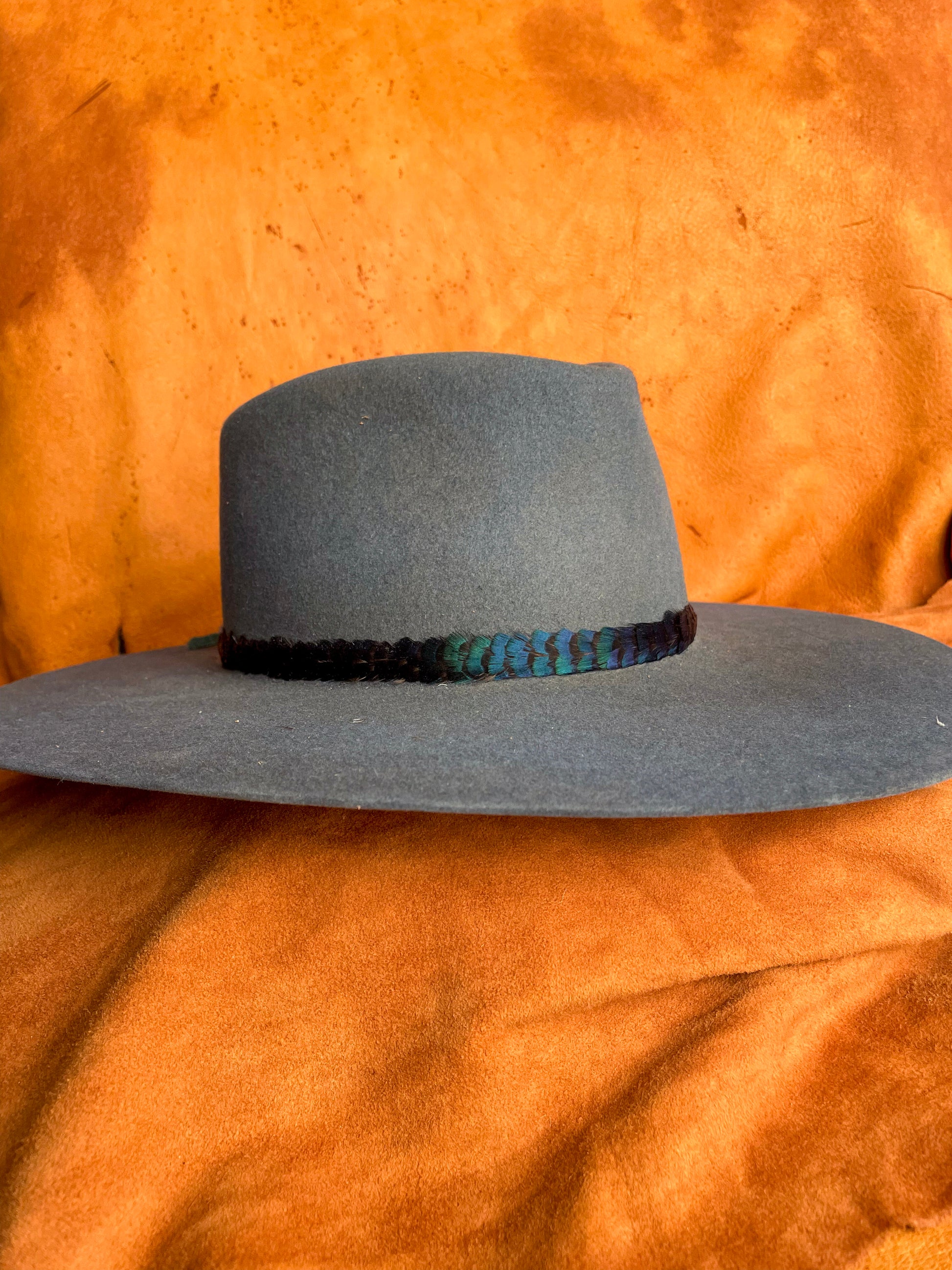 Minimalist feather band with jewel-toned color on a steel blue hat. 