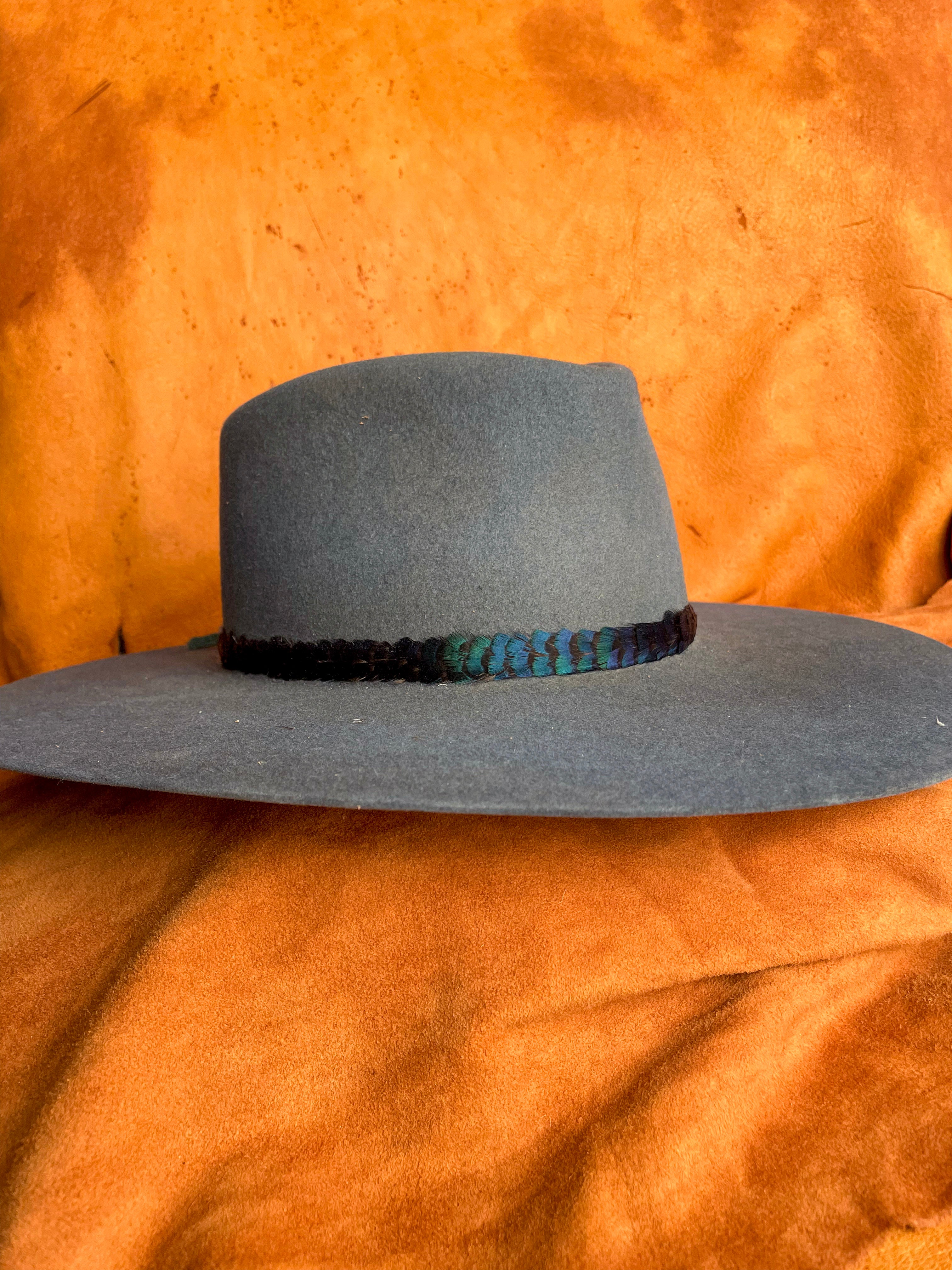 Minimalist feather band with jewel-toned color on a steel blue hat. 