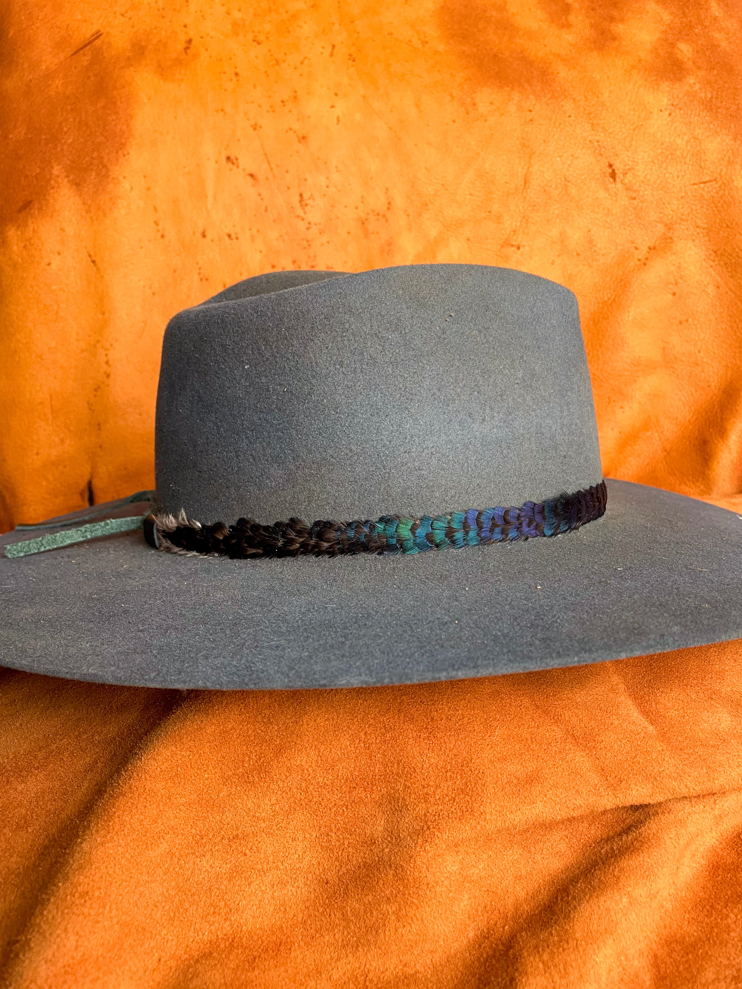Iridescent feather band with natural color shift on a steel blue felt hat, side view.